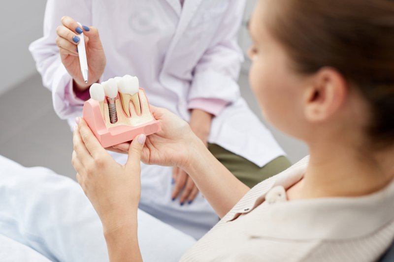 A dental patient holding a model of a dental implant