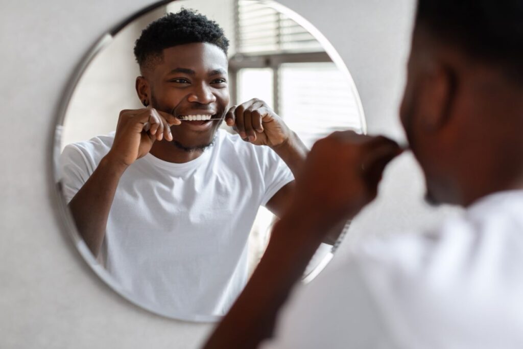 A man flossing in the mirror.